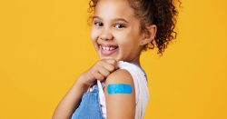 Smiling girl shows bandage due to a vaccination.