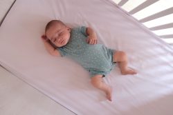 Baby sleeping on his back in a crib with no padding or blankets. 