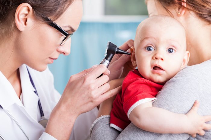 An infant has his ears examined by a pediatrician.