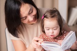 Mother holds her child on her lap as they read together.