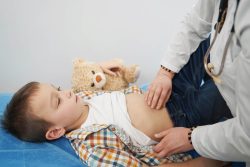 A child's stomach is examined by a doctor due to a tummy ache.