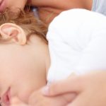 mother laying in bed with toddler who is sleeping